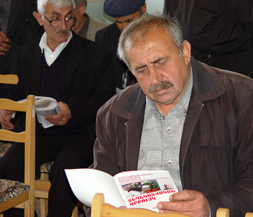 A local farmer reading Mardakert Agricultural Development Association information booklet